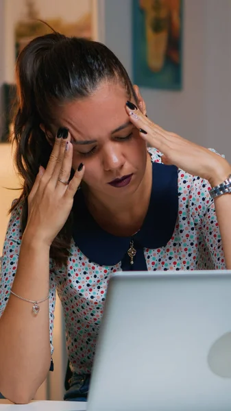 Mujer con dolor de cabeza trabajando desde casa hasta tarde —  Fotos de Stock