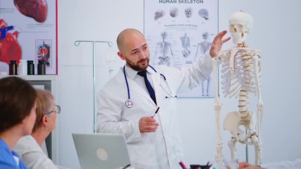 뼈 모형을 사용하여 신체의 뼈 기능성 아들을 보여 주는 전문 의사 — 비디오