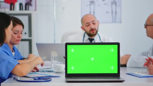 Équipe de médecins plaçant un ordinateur portable avec écran vert devant la caméra — Video