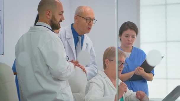 Equipo de médicos de pie en la sala de conferencias del hospital utilizando el ordenador portátil — Vídeos de Stock