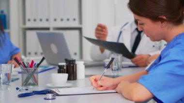 Radyolog iş arkadaşları tartışırken hemşire not alıyor.