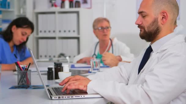 Lekarze piszący na laptopie informacje badawcze podczas dyskusji pracowników zespołu — Wideo stockowe