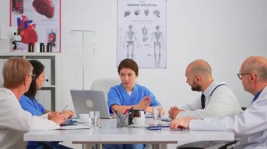 Hemşire konferans masasında oturup ekibe araştırma bilgilerini açıklıyor.