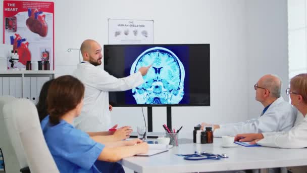 Médico jefe barbudo Cvalified explicando la estructura cerebral usando monitor — Vídeos de Stock