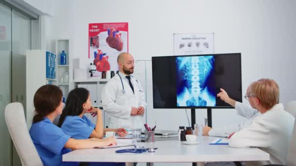 Doktorlar hastane yönetim kurulunda oturmuş dijital röntgen görüntüsüyle çalışıyorlar. — Stok video