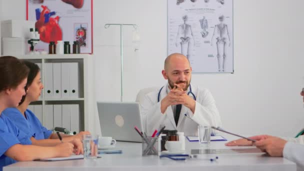 Specialistläkare som sitter på konferensbordet och diskuterar med teamet — Stockvideo