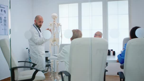 Médico aprendendo colegas funções ósseas corporais usando raio-x e esqueleto humano — Vídeo de Stock