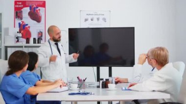 Beyin fırtınası sırasında dijital röntgeni analiz eden bir grup doktor.