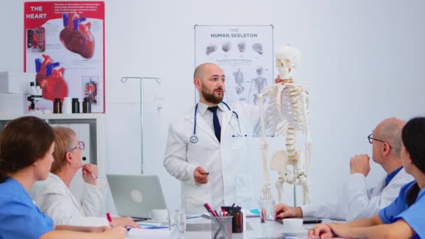 Médico médico hombre apuntando a la columna cervical del esqueleto humano — Vídeos de Stock