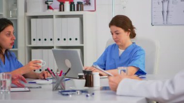 Hemşire konferans sırasında dizüstü bilgisayarda yazıyor ve gülümseyen kameraya bakıyor.