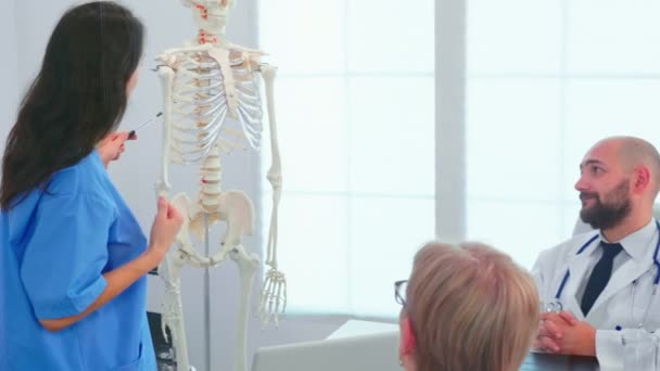 Infermiera donna che dimostra sullo scheletro di fronte ai chirurghi medici — Video Stock