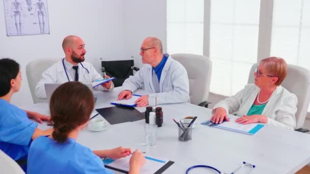 Médicos analizando lista de pacientes conversando con colegas — Vídeo de stock