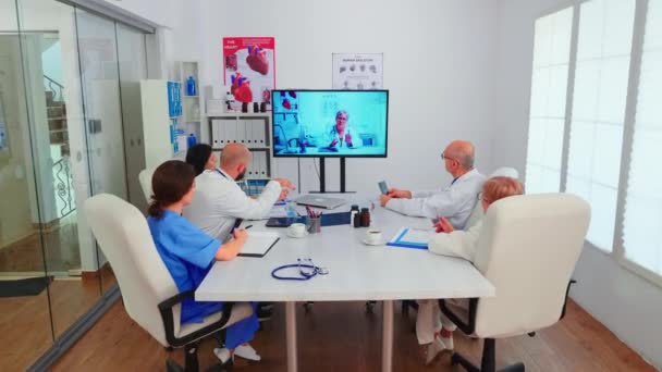 Группа врачей обсуждает с экспертом-медиком во время видеоконференции — стоковое видео