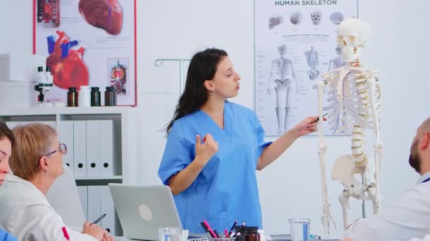 Doctor describiendo el diseño de la columna vertebral humana frente a sus colegas — Vídeo de stock