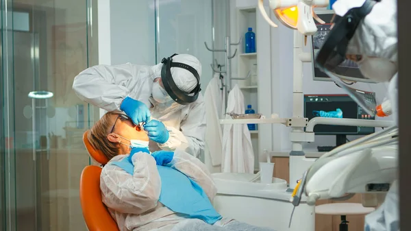 Zahnarzt mit geschliffenem Gesicht behandelt Zähne einer Seniorin — Stockfoto