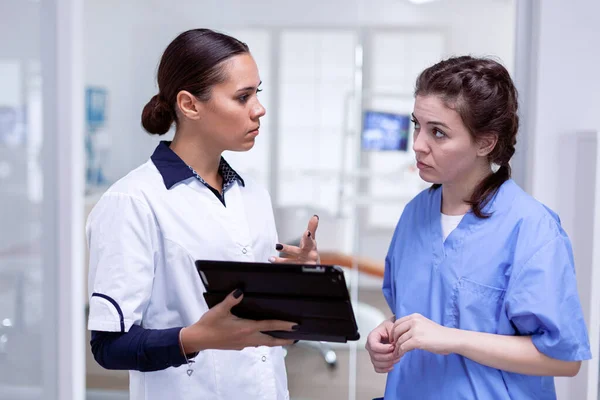 Дантист смотрит на медсестру, объясняющую инфекцию зубов — стоковое фото