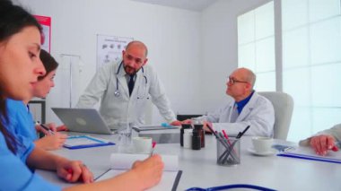 Sağlık personeli hastane ofisinde ekip çalışanıyla konuşuyor.