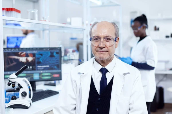 Scienziato anziano seduto sul posto di lavoro — Foto Stock