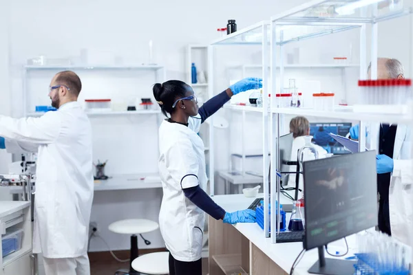 Африканці в біотехнологічній лабораторії тягнуться до скляної колби. — стокове фото