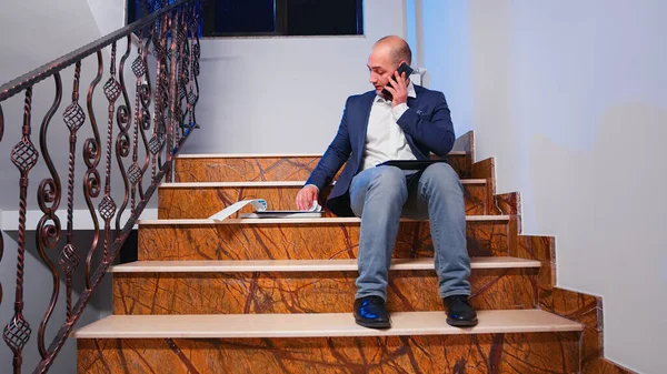 Ο άνθρωπος μιλάει στο smartphone και τον έλεγχο των ετήσιων εκθέσεων στις σκάλες — Φωτογραφία Αρχείου