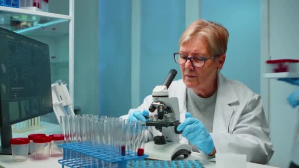 Kvinnlig forskare som tittar på prover under mikroskop — Stockvideo