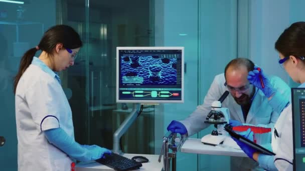 Nurse holding tablet computer and chemist using microscope — Stock Video