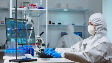 Koruyucu giysiler giyen bilim adamları kimya laboratuvarında çalışıyor.