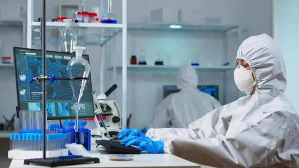 Ученые в защитных костюмах, работающих в химической лаборатории — стоковое фото