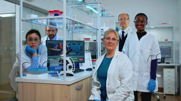Squadra di scienziati multietnici seduti in laboratorio a guardare la telecamera — Foto Stock