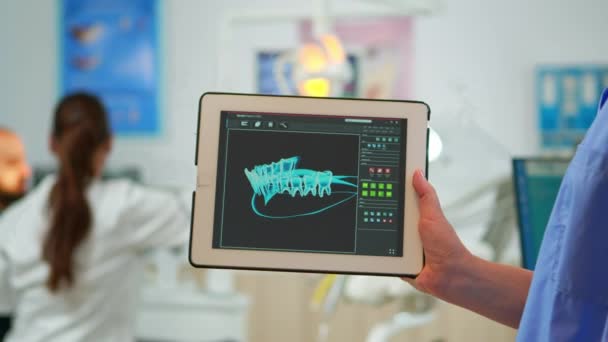 Zamknij asystent dentysty trzymając tabletkę z cyfrowym odciskiem palca dentystycznego — Wideo stockowe