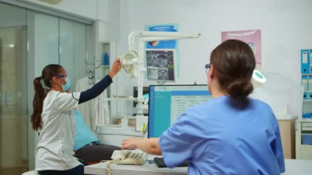 Enfermeira atendendo o telefone fazendo consultas odontológicas — Vídeo de Stock