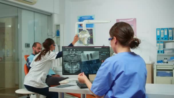 Stomatolog zdravotní sestra porovnávající radiografii při pohledu na počítač — Stock video