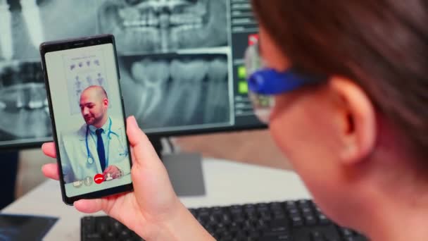 Gros plan de l'infirmière parlant en appel vidéo avec un médecin spécialiste en dentisterie — Video