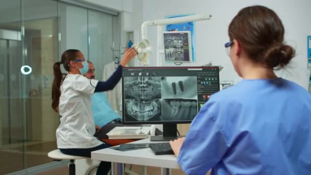 Infirmière analysant la radiographie numérique assise devant un ordinateur — Video