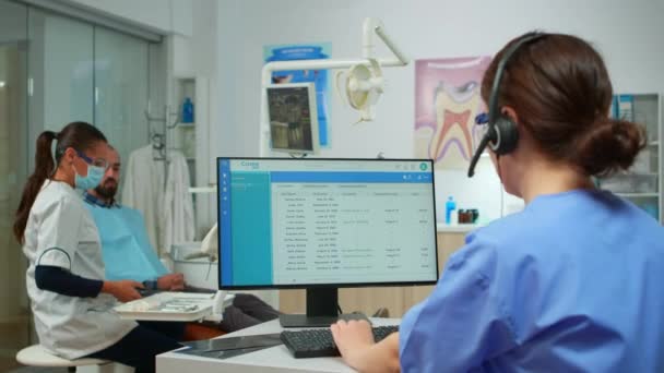 Sestra mluvit s pacienty, kteří používají sluchátka dělat zubní prohlídky — Stock video