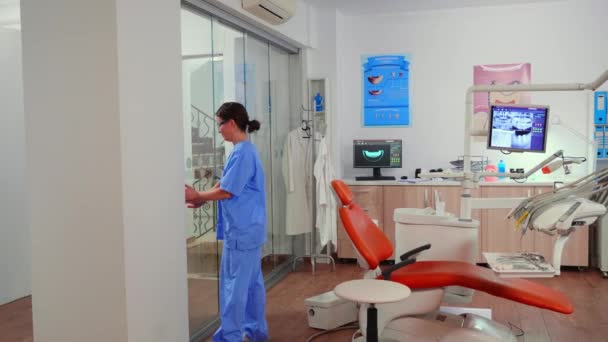 Sestra zvoucí pacienta v stomatologické místnosti ukazující ležet na židli — Stock video