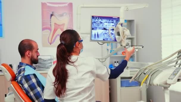 Стоматолог-врач зажигает лампу осматривая пациента — стоковое видео