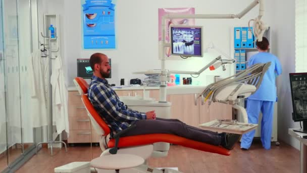 Медсестра ставить зубну пазуху людині перед стоматологічним оглядом — стокове відео