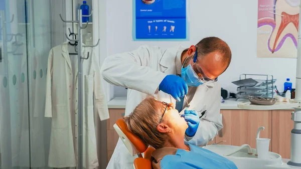 Ортодонт осматривает пациента с помощью стерильных стоматологических инструментов — стоковое фото