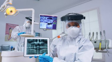 Diş muayenehanesindeki hasta doktoru yeni bir normal diş tedavisini tartışıyor.