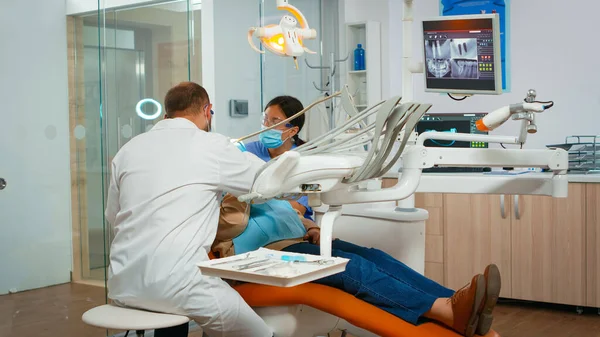 Дантист лечит зубы пожилой пациентке в клинике — стоковое фото