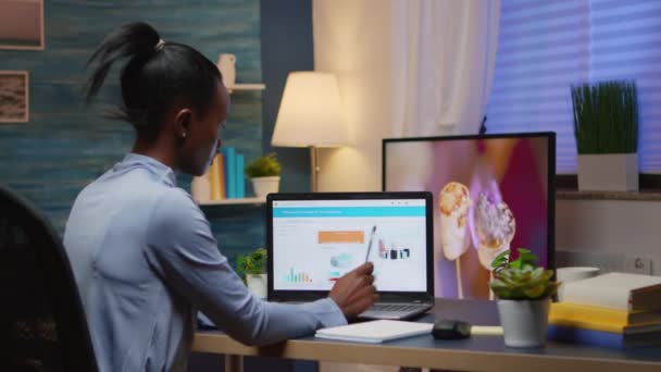 Mulher negra trabalhando em projeto financeiro a partir de casa usando laptop — Vídeo de Stock