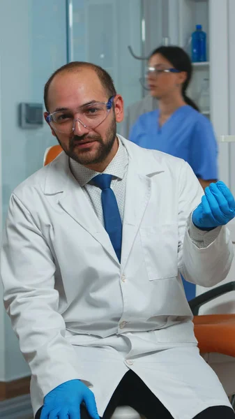 Médico dentista olhando para câmera conversando com pacientes — Fotografia de Stock