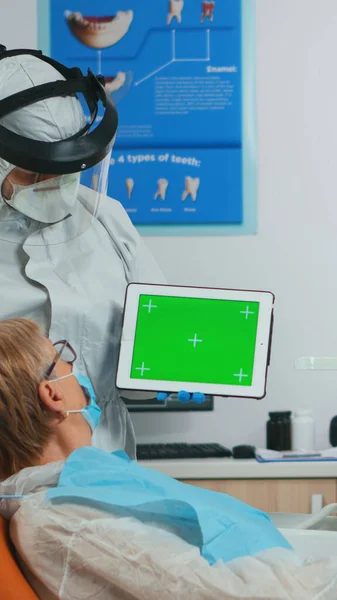 Стоматолог со щитом для лица, указывающим на зеленый экран — стоковое фото