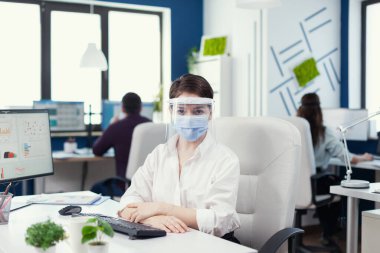 Girişimci yüz maskesi takıyor ve vizör kameraya bakıyor.