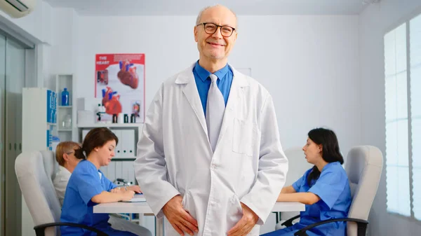 웃으면서 카메라 앞에 서 있는 노인 외과 의사의 모습 — 스톡 사진