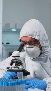 Biyolog doktor mikroskop kullanarak DNA örneğini kontrol ediyor.