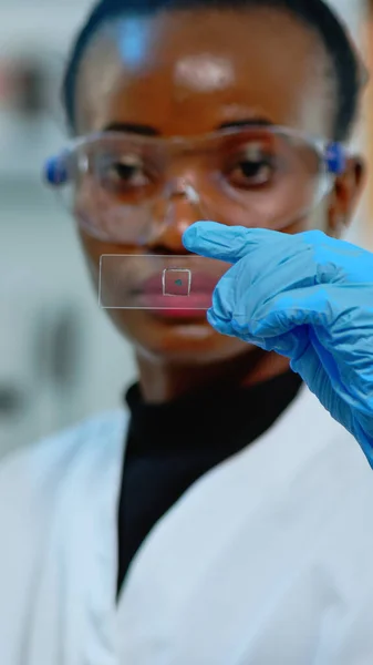 Czarny technik laboratoryjny robi eksperyment w laboratorium patrząc na wyniki — Zdjęcie stockowe