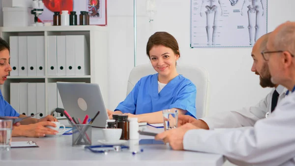 Infirmière écrivant sur ordinateur portable pendant la conférence et regardant la caméra sourire — Photo