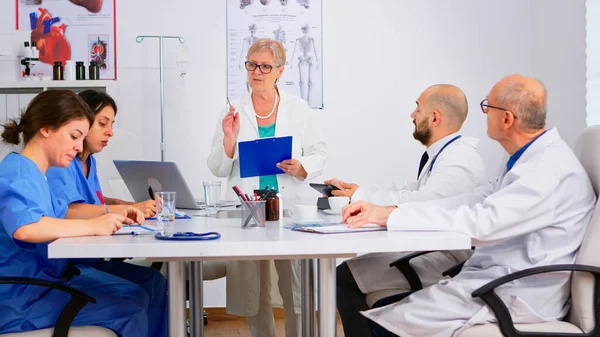 Volwassen arts presenteert nieuwe medische procedures staan aan het bureau — Stockfoto